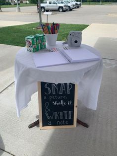 a white table topped with a sign next to a sidewalk