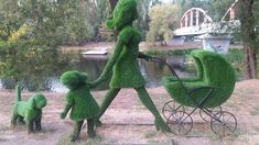 a woman is walking with her child in a stroller made to look like grass