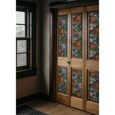 an open wooden door with floral designs on the glass and wood paneling, in front of a window