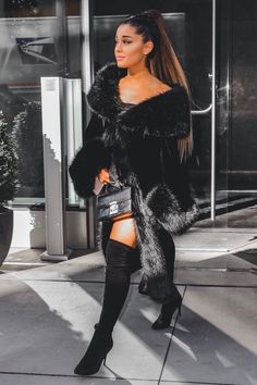 a woman is walking down the street in thigh high boots and a fur coat on