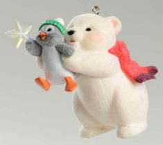 two stuffed animals are hanging from a christmas ornament on a string, one is holding the other