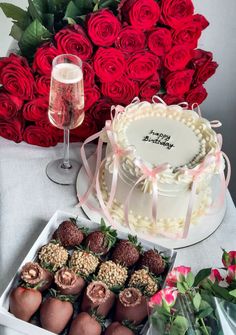 there is a cake and some strawberries in the box on the table with roses