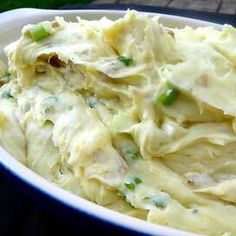 a white bowl filled with mashed potatoes and green onions