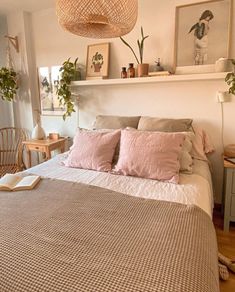 a bed in a bedroom with pink pillows and blankets on it's headboard