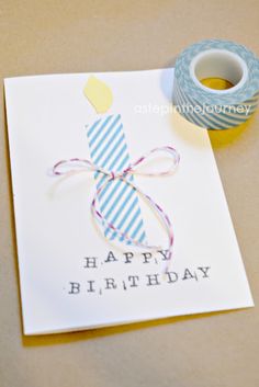 a birthday card with a candle on it next to a spool of thread and a roll of tape