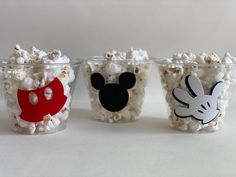 three plastic cups filled with popcorn and mickey mouse faces