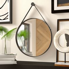 a mirror hanging on the wall next to a vase with a palm tree in it