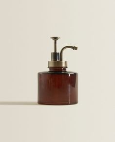 a brown soap dispenser sitting on top of a white wall