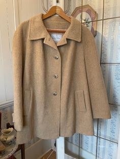 This lovely jacket by Surrey Classics, Canada, is made from a blend of 80 per cent wool, 10 per cent mohair and 10 per cent nylon - so warm and soft! - in classic camel beige. It has the original buttons on the front and matching buttons on the cuffs, two outside pockets, and is fully lined with light beige silky lining. The measurements, taken with the jacket lying flat, are: shoulder to shoulder, 20 inches; armpit to armpit, 24  inches; sleeves, 25 inches; length, 34 inches; bottom edge, 34 inches. In very good condition. Beige Winter Coat, Beige Coat, Beige Jacket, Wool Blend Jacket, Brown Jacket, Short Coat, Faux Fur Coat, Wool Jacket, Light Beige