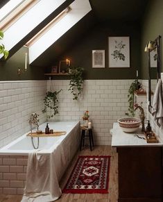 a bath room with a tub a rug and some plants on the wall next to it