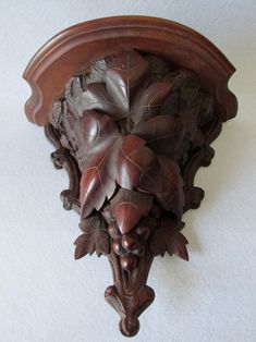 an ornate wooden wall hanging with leaves and acorns