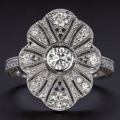 an antique style diamond ring with filigrees in the center and shoulders, on a black background