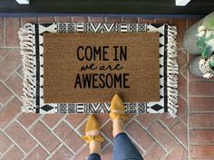 a person standing in front of a welcome mat that says come in we are awesome