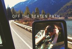 a person taking a photo in the rear view mirror of a car with mountains in the background