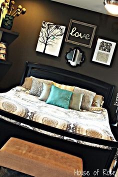 a bedroom with black walls and pictures on the wall above the bed, along with an ottoman