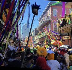 a crowd of people walking down a street next to tall buildings with colorful decorations on them