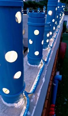 blue pipes with white lights on them are lined up along the edge of a building