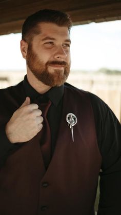 a man with a beard wearing a vest and brooch on his lapel pin