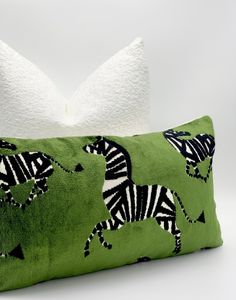 a green pillow with zebras on it and a white pillow in the back ground