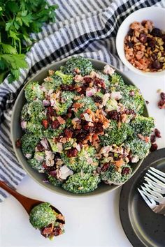 a bowl filled with broccoli salad next to two bowls of other food and utensils