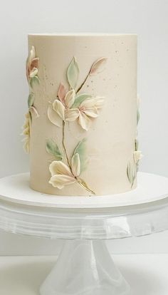 a white cake decorated with flowers and leaves