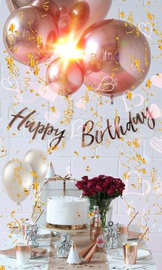 a birthday cake on a table with balloons and confetti in the air above it