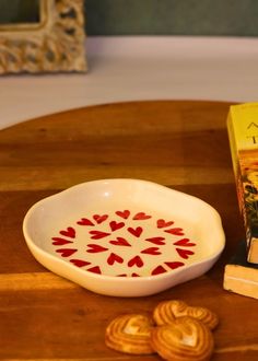 a wooden table topped with a white bowl filled with food next to a box of cookies