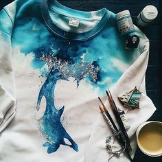 a t - shirt with an image of a tree on it next to some paint and brushes