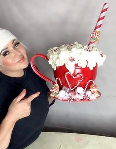 a woman is holding up a mug with whipped cream and candy canes on it