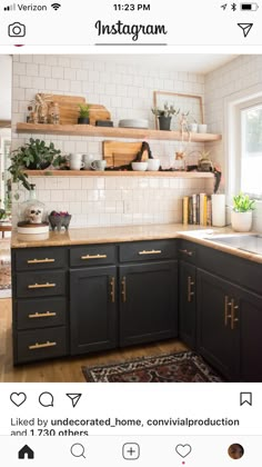 a kitchen with black cabinets and white subway backsplash, gold pulls on the doors