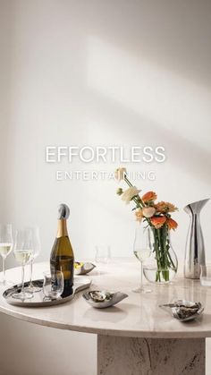 a table topped with wine glasses and plates covered in flowers next to a bottle of wine