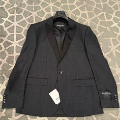 Brand New 100% Authentic Balmain Tuxedo Jacket. Crafted From High-Quality Wool, This Gray Jacket Features A Slim Fit Design With A One-Button Front Button Style And Notch Satin Black Lapel. The Jacket Is A Size 58 And Is Perfect For Any Formal Occasion. This Suit Jacket Is Suitable For Men Who Want To Dress To Impress. The Jacket Is Part Of The Balmain Brand, Known For Its Quality And Stylish Designs. Perfect For Any Man Who Wants To Look Sharp And Sophisticated. Pit To Pit 22.5 In Top To Bottom Gray Tuxedo, Grey Tuxedo, Button Style, Tuxedo Jacket, Gray Jacket, Formal Occasion, Mens Suits, Blazer Suit, Dress To Impress