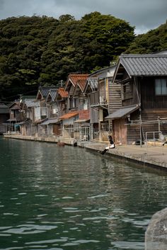 a row of wooden houses sitting next to a body of water with trees in the background