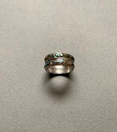 This gorgeous ring features inlaid abalone stones set in sterling silver. It is fairly old, and the inside of the band has some natural tarnishing that I could not remove, but it does not affect the appearance of the ring. It is not marked and is size 7.25. Silver Opal Ring With Inlay, Silver Opal Ring With Inlay For Anniversary, Round Patina Rings For Anniversary, Anniversary Silver Opal Ring With Inlay, Sterling Silver Patina Ring, Silver Patina Jewelry For Weddings, Silver Stackable Turquoise Ring For Anniversary, Vintage Silver Multi-stone Opal Ring, Vintage Silver Jewelry With Abalone Shell