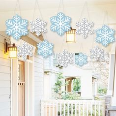 snowflakes are hanging from the front porch of a house with lanterns on it