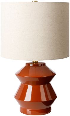 an orange table lamp with a white shade on the base and a beige lampshade