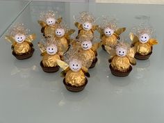 small gold cupcakes with faces and bows on them are sitting on a glass table