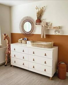 a giraffe is standing next to a dresser in a room with orange walls