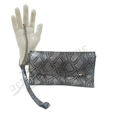 Rock this stylish, open all, 100% handmade fold-over wristlet/clutch with any outfit of your choice. This is crafted from shiny and reflective metallic reptile print cowhide leather. It features 2 detachable wrist straps(leather strap and a chain strap) with silver-tone hardware. Can be carried as a clutch without the strap. * Wristlet/clutch * Metallic color * Size(s): 9.25"W × 4.5"H × 0.75"D (Small) 11"W × 5.25"H × 1"D (Large) * Button style/open style * Snap closure * Silver-tone hardware * G Evening Clutch With Wrist Strap, Modern Clutch With Wrist Strap, Chic Silver Clutch With Silver-tone Hardware, Evening Clutch Wristlet, Silver Clutch With Magnetic Closure, Chic Evening Wristlet In Rectangular Shape, Trendy Rectangular Clutch With Wrist Strap, Trendy Clutch With Wrist Strap, Rectangular Clutch With Wrist Strap For Formal Events