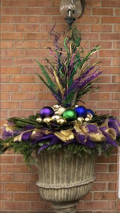 a potted plant with ornaments in it sitting next to a brick wall and clock