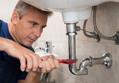 a man fixing a sink in a bathroom