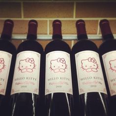 several bottles of hello kitty wine are lined up in a row against a brick wall