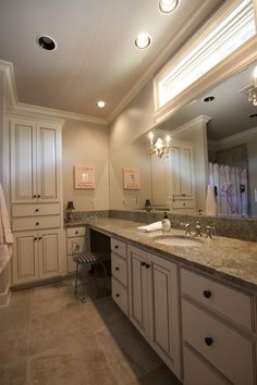 a large bathroom with marble counter tops and white cabinets