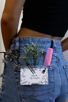 a pair of scissors in the back pocket of someone's jean pants with a plant growing out of it