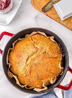 a baked dish in a red pan on a white marble counter top with utensils