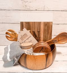 a wooden bowl with spoons and other items in it