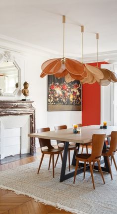 a dining room table and chairs in front of a fire place with a painting on the wall