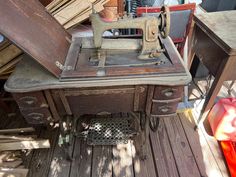 an old sewing machine sitting on top of a wooden table next to a pile of junk