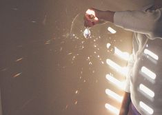 a person holding a sparkler in their hand with the sun shining through it and some light coming from behind