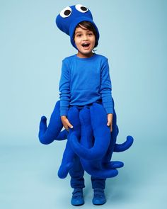 a little boy in a blue outfit with an octopus on his back and eyes wide open